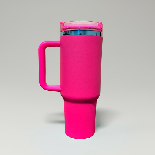 A bright pink travel mug with a matching pink lid and handle, featuring a metallic blue interior rim, shown on a neutral gray background.